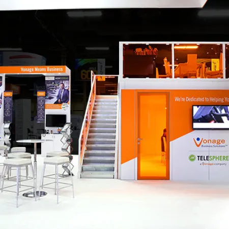Vonage business solutions booth with orange and white colors, seating area, and promotional displays at event.