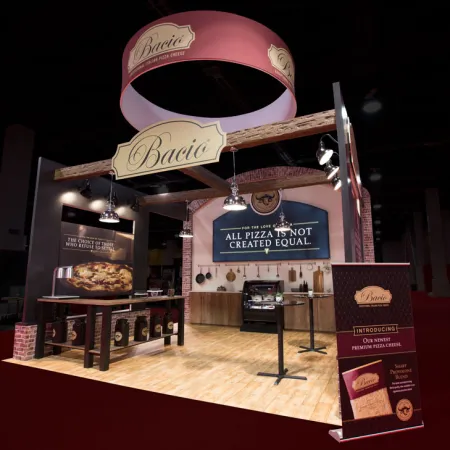 Bacio pizza booth with hanging signs and banner showcasing premium pizza cheese and slogan in event hall.