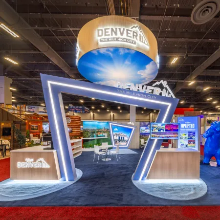 Modern Denver tourism booth with illuminated geometric entrance and promotional displays at convention center