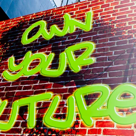 Bright green graffiti saying Own Your Future on a red brick wall near a blue window frame.