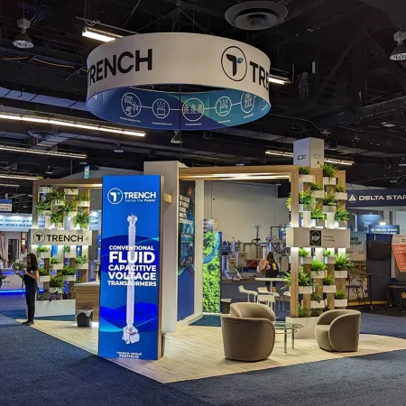 Trench exhibition booth at trade show featuring blue signage, product display, and seating area with plants.