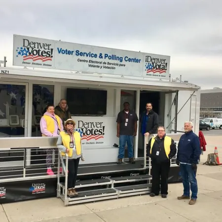 Group of election workers standing outside Denver Votes voter service and polling center kiosk