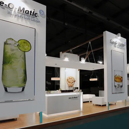 Modern trade show booth for Ice-O-Matic featuring large drink images and illuminated signs in a sleek setting