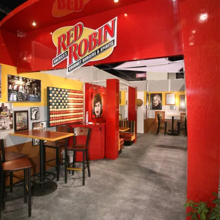 Red Robin restaurant interior with red and yellow decor, tables, chairs, and framed artwork on walls.