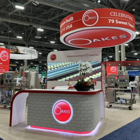 Oakes trade show booth with red and white branding celebrating 79 years, featuring industrial machinery and displays.