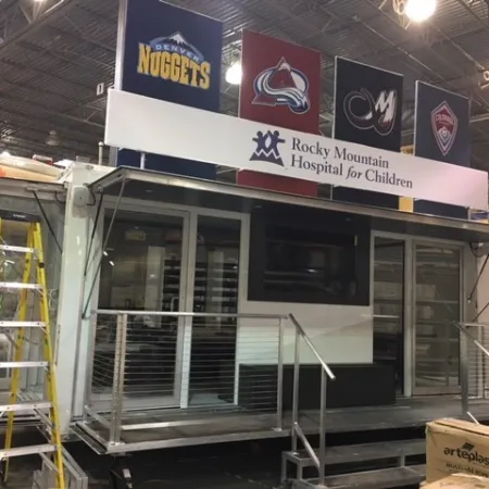 Mobile unit for Rocky Mountain Hospital for Children with sports team banners in a warehouse setting.