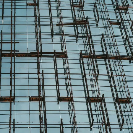 Scaffolding with rusty metal poles in front of a building under construction against a clear sky.