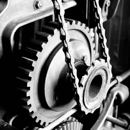 Close-up of interconnected metal gears and chains in a mechanical system with high contrast black and white effect
