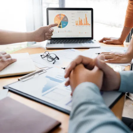 People analyzing financial charts and graphs on laptop and documents during a business meeting.