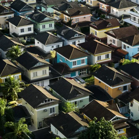 Aerial view of a residential neighborhood with colorful houses and lush green trees under daylight.