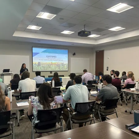 Group of people attending a leadership workshop in a modern conference room with a presenter and projection screen.