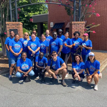 a group of people wearing matching blue shirts and posing for a photo