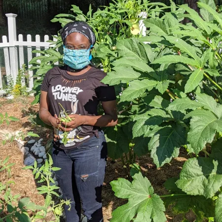 a man wearing a mask and standing in a garden