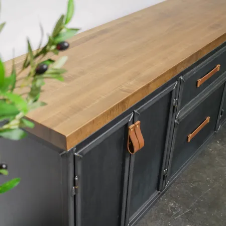 Wooden cabinet with leather handles and matte black doors in a modern industrial style interior.