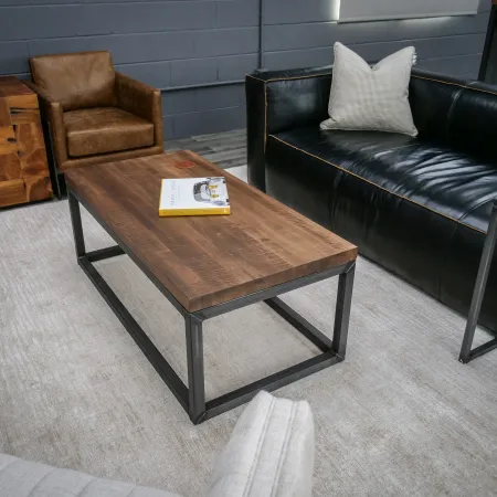Modern living room with leather sofa, wooden coffee table, brown armchair, and light area rug.
