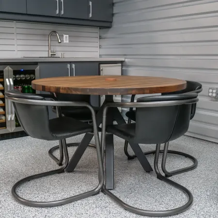Modern round wooden table with black metal base and four black chairs in a sleek gray kitchen area.