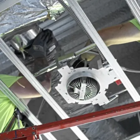 Construction workers installing recessed lighting in ceiling framework wearing safety gear on scaffold.