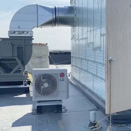 Roof-mounted HVAC units including an industrial exhaust fan and LG air conditioning unit next to an open door.