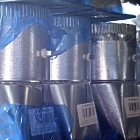 Metal duct pipes wrapped in blue plastic film arranged in a row in an industrial setting