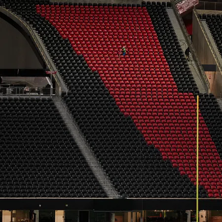 Red and black stadium seats with one person seated, featuring an Atlanta Falcons logo near the field goal post.