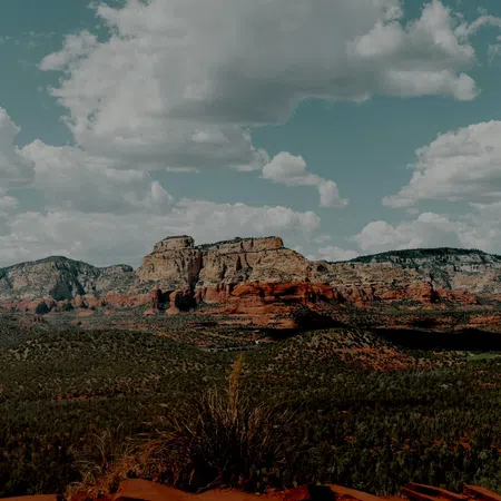 Panoramic view of red rock formations under a blue sky with scattered clouds in a desert landscape
