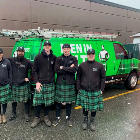 a group of men in kilts standing in front of a green truck