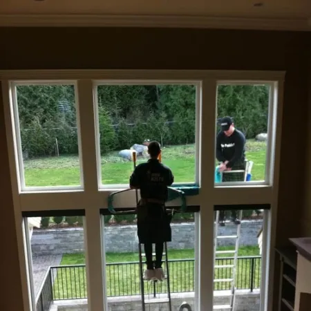 a couple of people standing in a room with windows and a railing