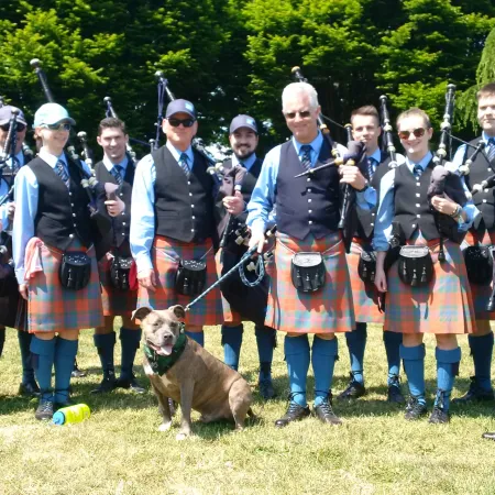 a group of people in kilts with a dog