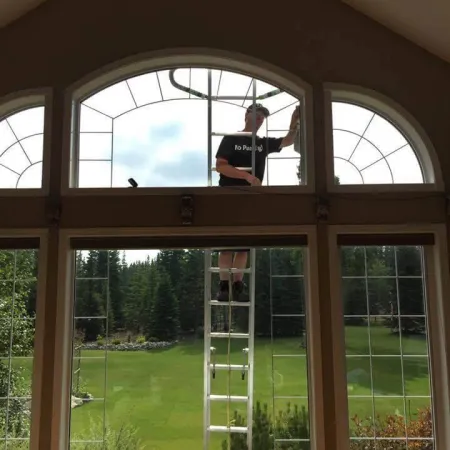 a person standing on a ladder in a room with windows