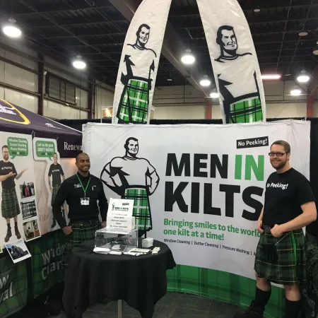 a couple of men standing next to a table with a sign