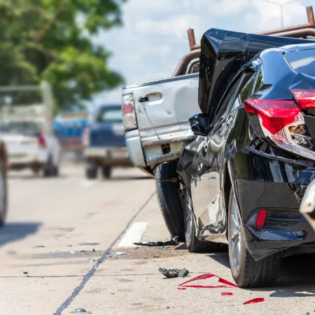 Rear-end collision involving multiple cars on a road with visible damage and debris scattered.