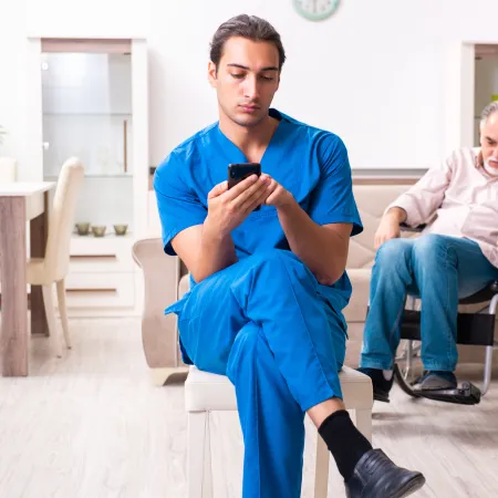 Man driving car while holding and looking at a smartphone, wearing a seatbelt and gripping steering wheel.