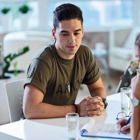 Young man in army shirt consulting with healthcare professional in modern medical office setting