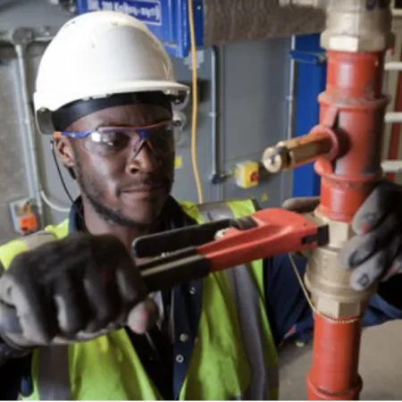 a person wearing a hard hat and safety goggles holding a pipe