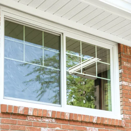 a white slider window with accent grills on a brick house