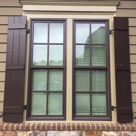 a window with glass panels and brown board and batten shutters