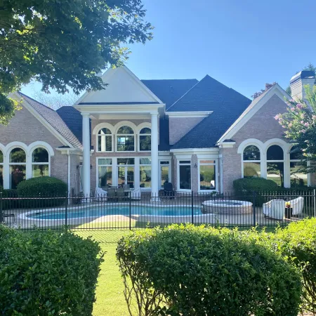 a large house with a fenced off pool and large white fiberglass replacement round top windows