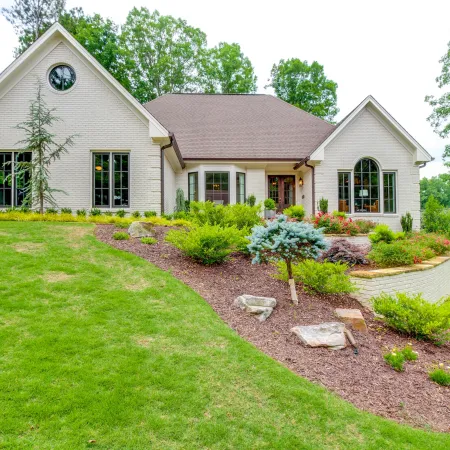 white brick home with fiberglass bronze windows and beautiful landscaping