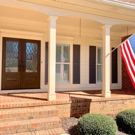 Brick front porch with double front doors with stained wood and privacy glass