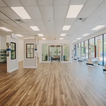 Bright spacious showroom with wood flooring displays windows and doors, large glass panels, and modern lighting.