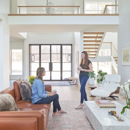 2 women in a living room with black modern French Doors behind them