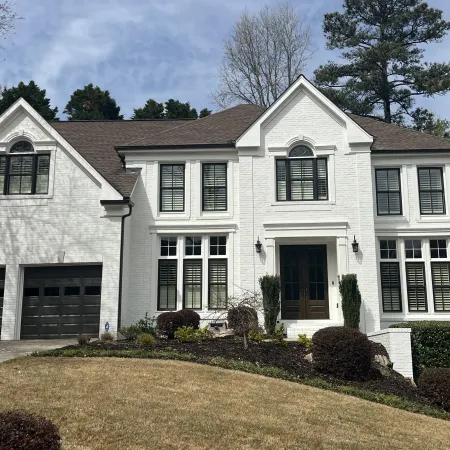 Elegant white house with large windows and neat landscaping on a sunny day.