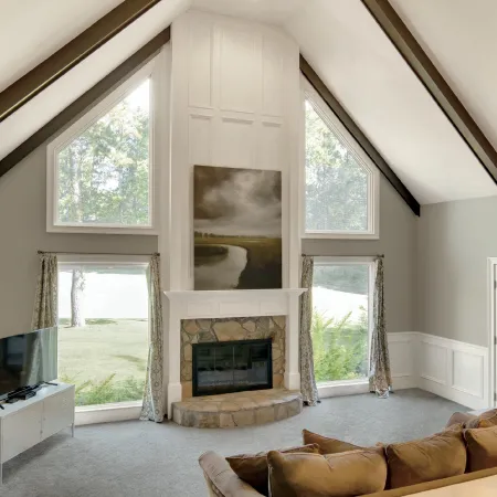 a living room with a fireplace and special shape fixed picture windows on either side