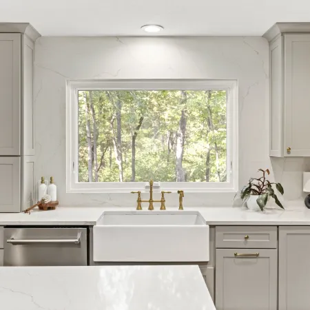a kitchen with white cabinets and a white fiberglass awning window above the sink