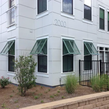 A white apartment building with commercial Bahama shutters