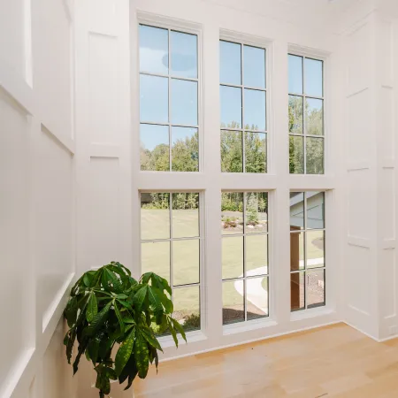 Bright corner with large windows showcasing a green lawn and a potted plant on light wood flooring.