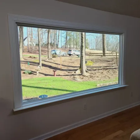 a large fiberglass picture window with a view of a yard and trees outside