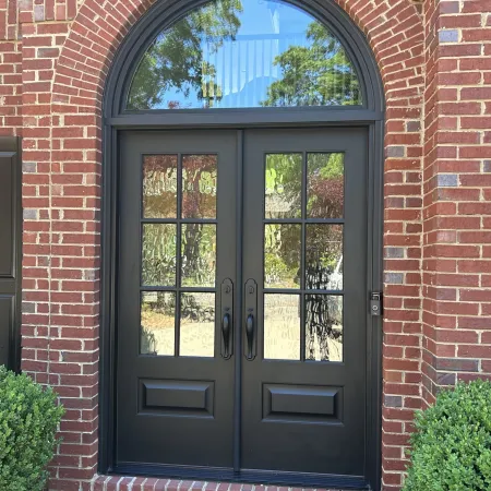 Brick house with black double entry doors below an arched transom