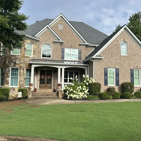 Charming two-story brick house with lush green lawn and decorative landscaping.