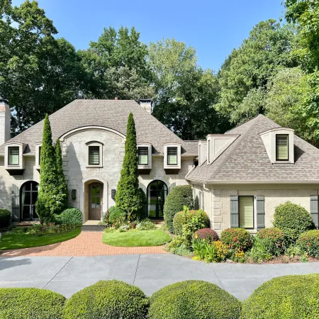 Elegant stone house with black casement windows and lush greenery